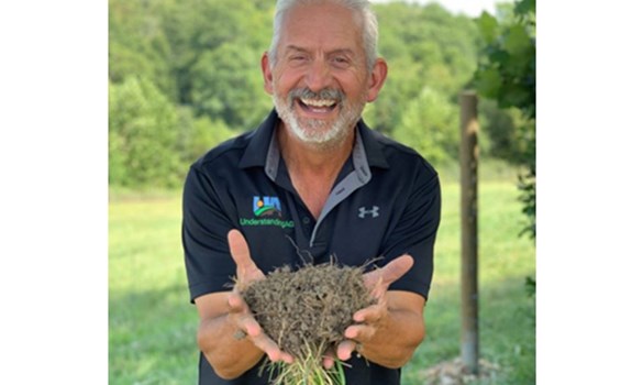 Ray Archuleta holding clod of soil and laughing at camera